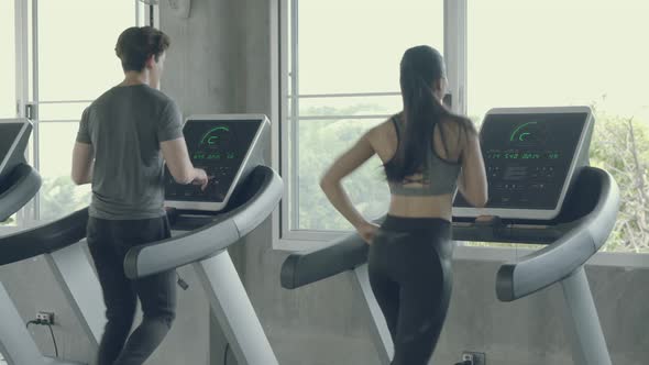 Asian young man and woman doing cardio exercise training with running on treadmill in sport gym. alt