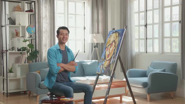 Asian Artist Man Crossing His Arms, And Smiling After Finish Painting A Girl On The Canvas alt