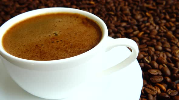 Cup with coffee on the background of coffee beans. alt