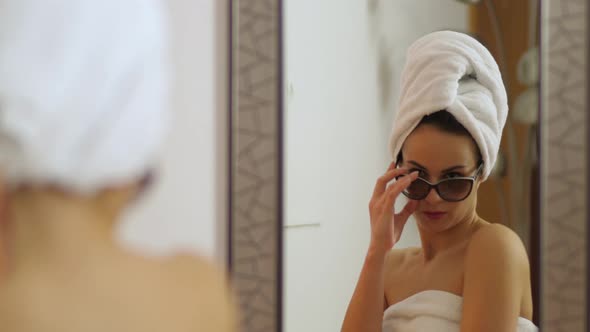 Young attractive woman with bath towel on her head and sunglasses for fun is dancing