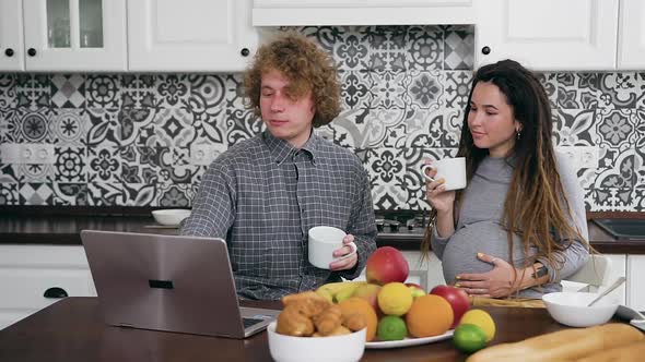 Family which Drinking Tea in Modern Kitchen and Simultaneously Using Laptop alt