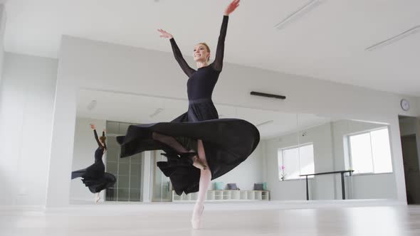 Caucasian female ballet dancer practicing ballet during a dance class in a bright studio alt