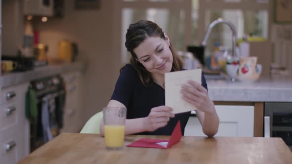 Young adult female opening Valentine's Day Card at Kitchen table