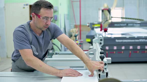 A man works in the assembly shop on a circular saw, neglecting safety alt