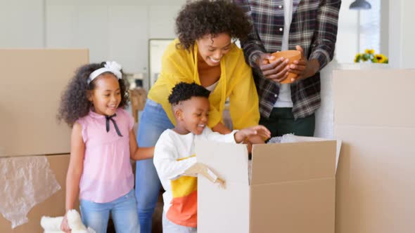 Front view of black family unpacking cardboard boxes at comfortable home 4k alt