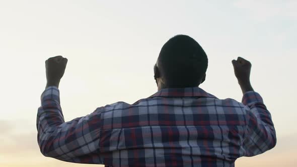 Black Man Rising Hands Up Showing Success Gesture, Winner, Magic Hour, Back-View