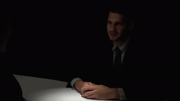 Businessman making handshake with partner in dark room after confidential meeting