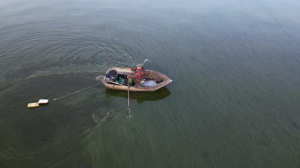 A Fisherman in a Boat Catches Fish in the Sea alt
