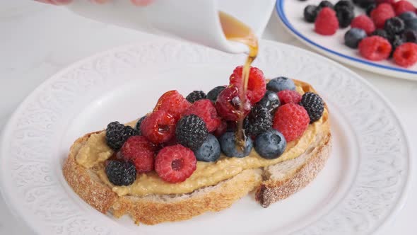 Cooking toast with peanut butter, berries and maple syrup.