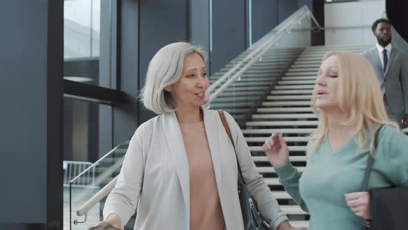 Happy Middle-Aged Lady Meeting and Hugging Female Friend at Airport alt