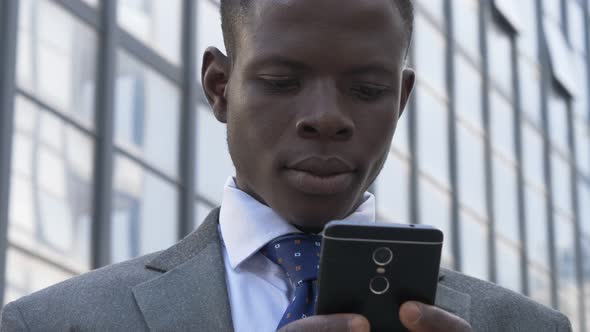 Busy black american business man typing on his smartphone in the street-close up alt