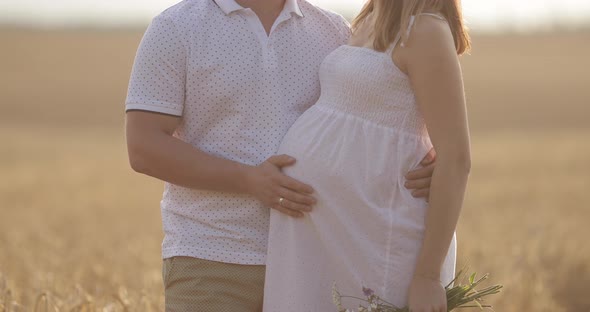 Portrait of Young Pregnant Couple in Field