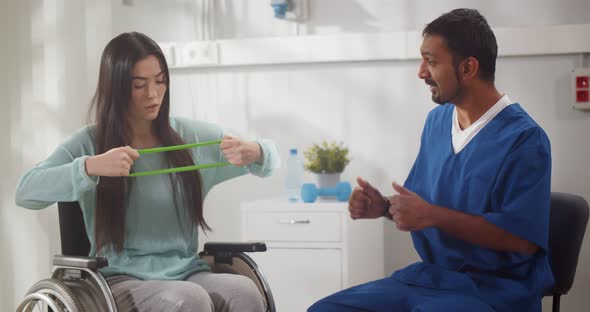 Disabled Young Female Patient in Wheelchair During Rehabilitation with Therapist alt