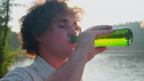 Man Drinking Beer and Speaking with Friends at Lake Party alt