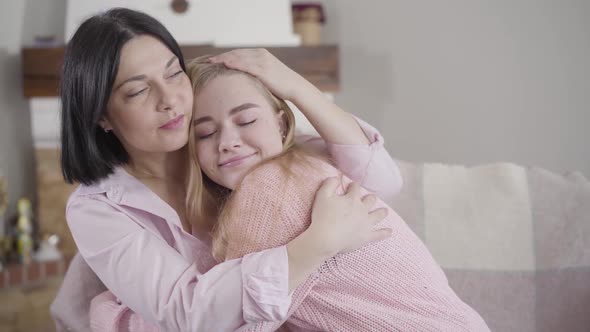Portrait of Beautiful Brunette Caucasian Woman Hugging Young Girl and Touching Her Nose. Positive alt