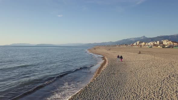 Elderly couple holding hands and enjoying retirement walking on a beautiful beach during sunset alt