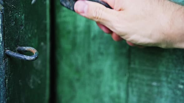 Caucasian Man is Opening a Wooden Door in a House Locked on a Hook