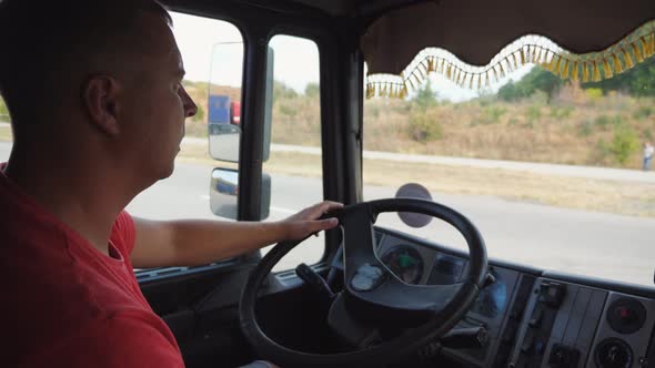 Lorry Driver Operating the Truck Through Countryside at Sunny Day alt