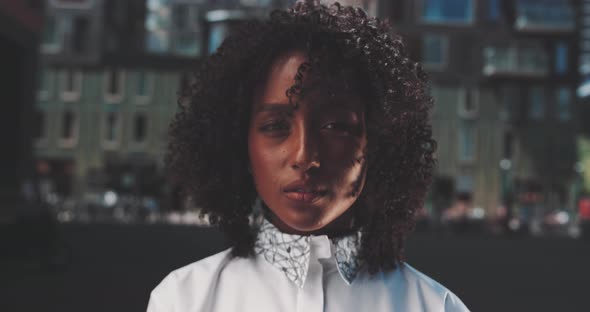 Attractive african woman with curly hairstyle looks directly at camera alt