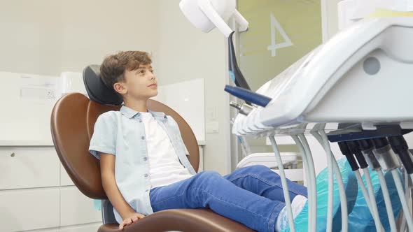 Lovely Young Boy Sitting in Dental Chair Waiting for Teeth Examination alt