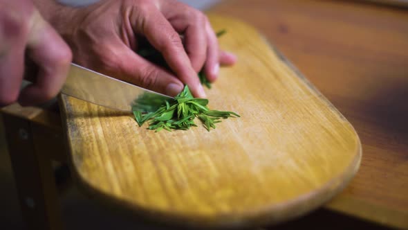 Cook Cuts Tarragon on a Wooden Board with a Kitchen Knife alt