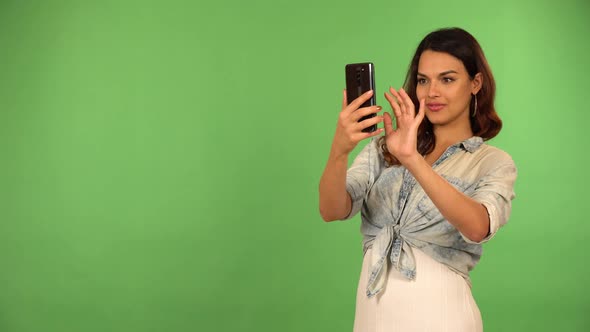 A Young Beautiful Caucasian Woman Takes Pictures with a Smartphone  Green Screen Background