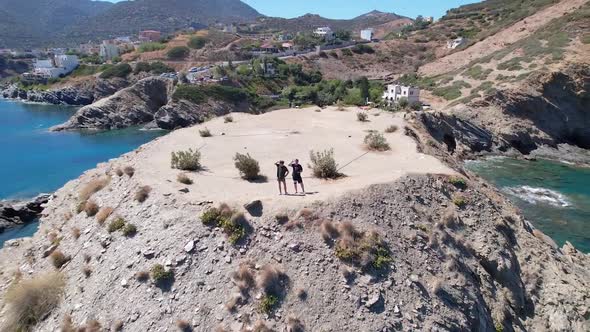 Drone flies over the rocky nature and blue sea with swimmers and boat in sight. Volcanic archipelago alt