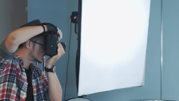 Profile View of Caucasian Photographer Working in Studio with Soft Box in the Background alt