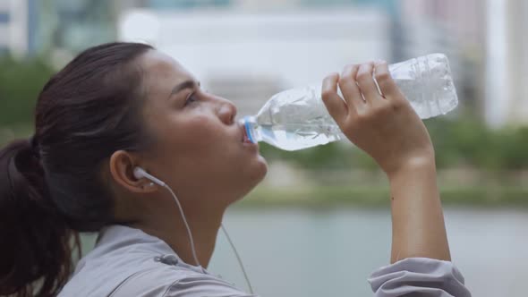 Young Asian woman runner drink water after running.