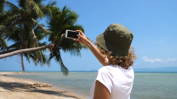 Woman Tourist Taking Photo Of The Beach Using Smartphone alt