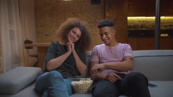 African American Boyfriend Checking Mobile Phone While Watching Movie and Eating Pop Corn with His alt