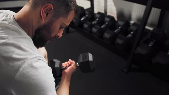 Bearded athlete athletic man bodybuilder training shoulders in the gym with dumbbells alt