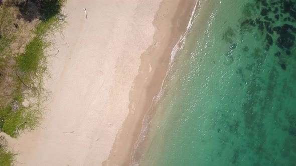 Aerial shot of turquoise waters washing up at white sandy beach Thailand - camera rotating with pede alt
