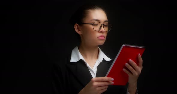 Business Woman is Outraged By What She Has Read in a Red Notebook