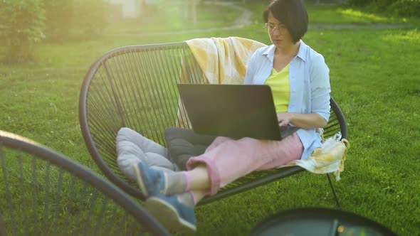 Freelance woman works on laptop at home in the backyard