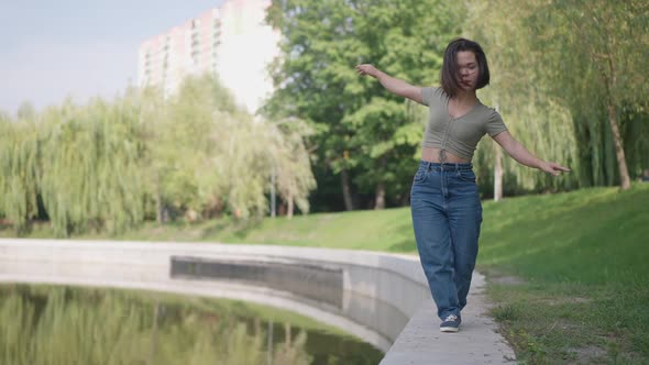 Wide Shot Joyful Little Woman Walking on Lake Shore in Slow Motion Having Fun in Spring Summer Park alt
