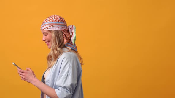 Positive blonde woman hippie texting by phone alt