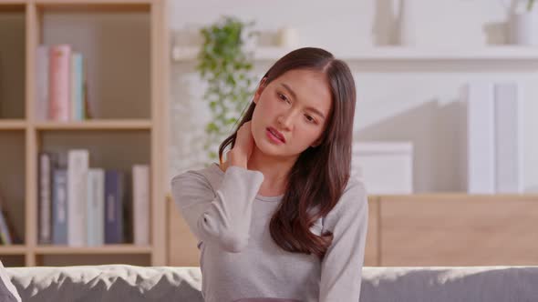 An Asian woman  do self massage at her neck and shoulders alt