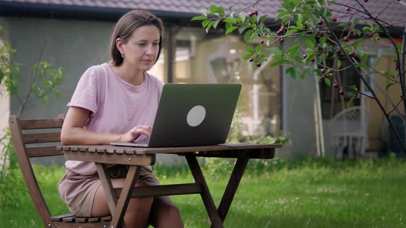A Woman Works In Garden With Her Laptop alt