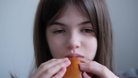 Little Girl Teenager Eating Burger at Home on the Couch