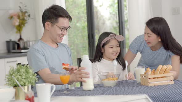 Parent and daughter eating Cereals with milk having breakfast morning in kitchen. alt