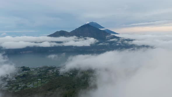 Slow Aerial Dolly Shot Flying Through the Clouds Past Small Valleys Towards Lake Batur and Mount alt