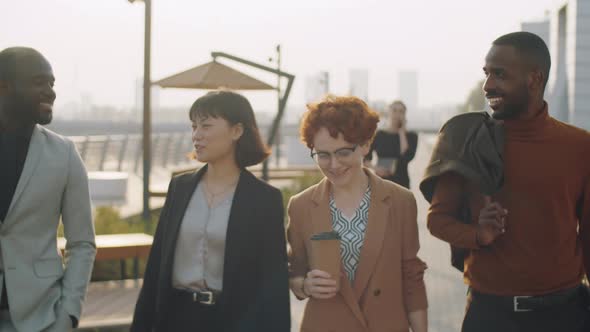 Multiethnic Business People Walking and Talking in Street alt