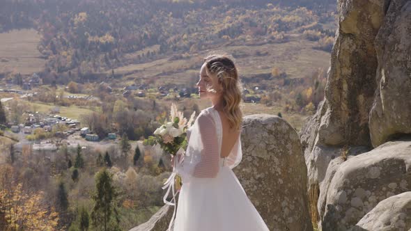 Pretty Young Bride Wearing Long White Dress Walking Against Mountains View alt