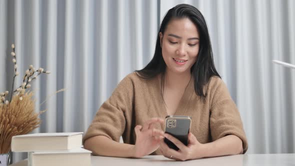 Cheerful girl checks social media on her phone and surfs online apps.