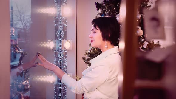 Woman Looks Out the Window at Passersby Near the New Year Tree Cinematic Shot alt