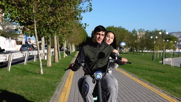A Young Couple is Riding a Electro Bike at Urban Park