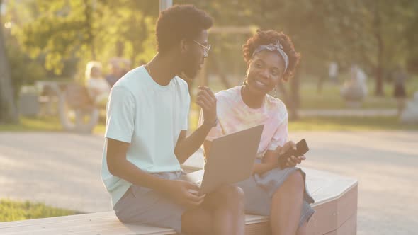 Afro-American Friends Chatting on Bench in Park alt