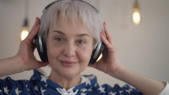Headshot Portrait Smiling Slim Mature Woman in Headphones Moving Head Smiling Looking at Camera alt