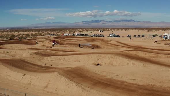 Motocross rider catching air on ramp in Mojave Desert, AERIAL SLOW MOTION alt